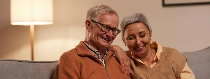 Senior couple enjoying time together on laptop indoors, smiling and relaxed.