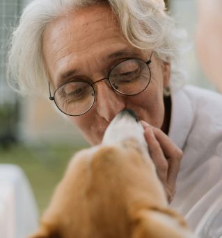 Heartwarming moment of an elderly man bonding closely with a pet Corgi outdoors.