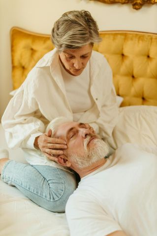 Senior woman comforting her partner in bed, offering gentle care and support.